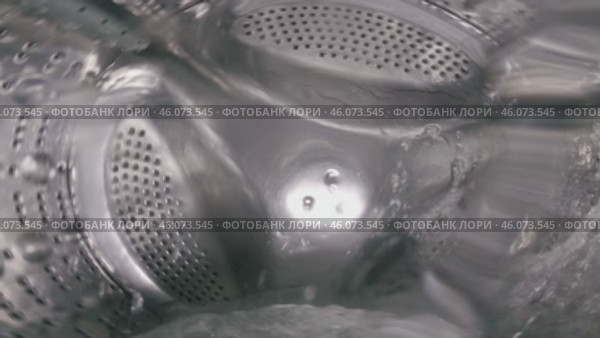 Close-up of a rotating drum of a washing machine filled with water. View from inside the washing machine. Стоковое видео, видеограф Воловодов Владимир / Фотобанк Лори