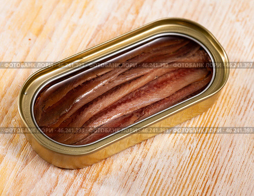 Close-up of canned anchovy fillet in oil on wooden surface. Стоковое фото, фотограф Яков Филимонов / Фотобанк Лори