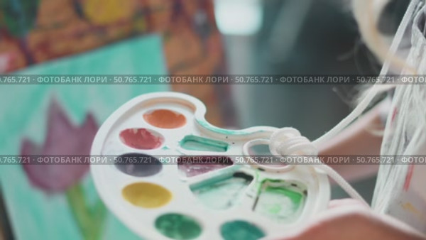 Close-up of child choosing colors from palette. Moment of inspiration reflects joy of self-expression, imagination, and creativity in a supportive space. Стоковое видео, видеограф Енваев Андрей / Фотобанк Лори