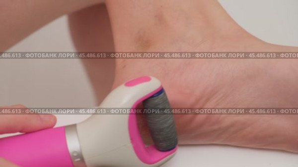 Close-up of electric foot file being used to remove calluses from a heel. Skincare and personal grooming concept. A woman of 40 years old. Стоковое видео, видеограф Андрей Журавлев / Фотобанк Лори