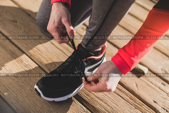 close up woman tying her shoelaces wooden floor. Стоковое фото, агентство Ingram Publishing / Фотобанк Лори