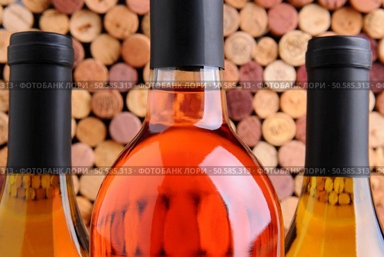 Closeup of three wine bottles two chardonnay and one red in front of a mass of out of focus corks. Стоковое фото, агентство Ingram Publishing / Фотобанк Лори