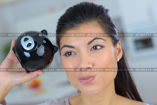closeup of woman shaking piggybank dubious expression. Стоковое фото, агентство Ingram Publishing / Фотобанк Лори