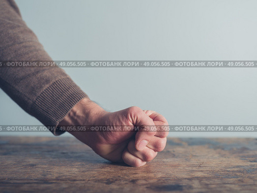 Closeup on a man slamming his fist on a wooden table. Стоковое фото, агентство Ingram Publishing / Фотобанк Лори