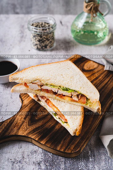 Club sandwich with chicken meat, tomato and lettuce on a board on the table vertical view. Стоковое фото, фотограф Елена Руй / Фотобанк Лори