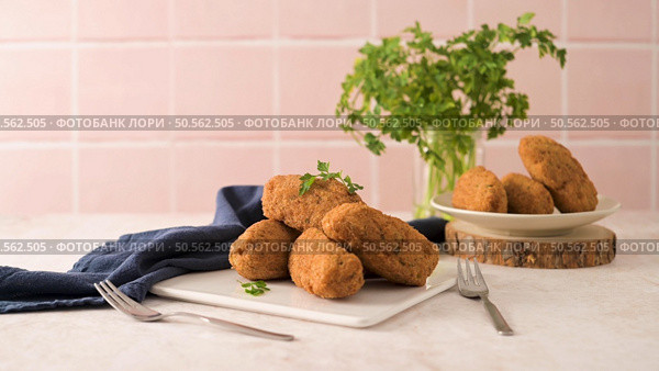 Cod dumplings, or "bolinhos de bacalhau" and parsley leaves on white ceramic dishes in a kitchen counter top. Стоковое фото, агентство Ingram Publishing / Фотобанк Лори
