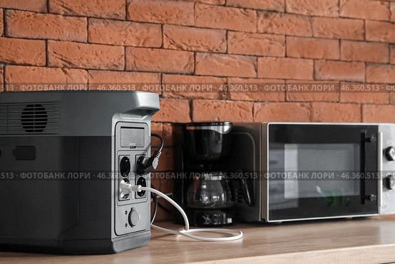 Coffee machine and microwave oven plugged in portable power station on counter in kitchen. Стоковое фото, фотограф Pixel_shot / Фотобанк Лори