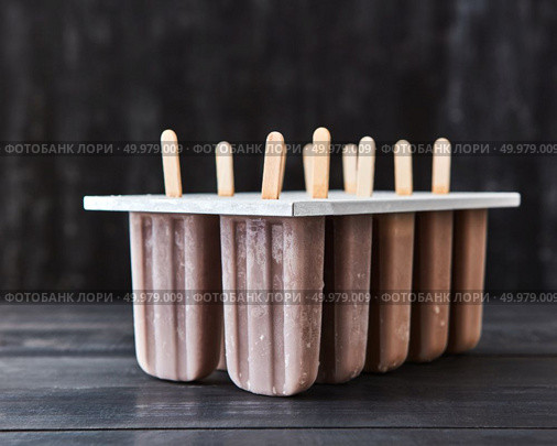 Cold summer dessert. Homemade chocolate ice cream popsicle on a stick in a mold on a dark wooden table with a copy of the space for text.. Plastic molds with coffee ice cream on a stick presented on a dark wooden background with copy space. Стоковое фото, агентство Ingram Publishing / Фотобанк Лори