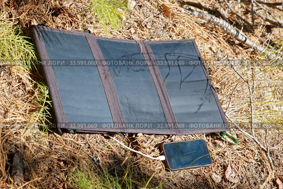 Collapsible solar panel charges a smartphone. Стоковое фото, фотограф Круглов Олег / Фотобанк Лори