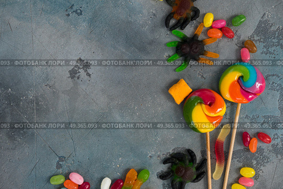 Colorful halloween candies on stone. Trick and treat - halloween scary candies border on stone with copy space. Стоковое фото, агентство Ingram Publishing / Фотобанк Лори