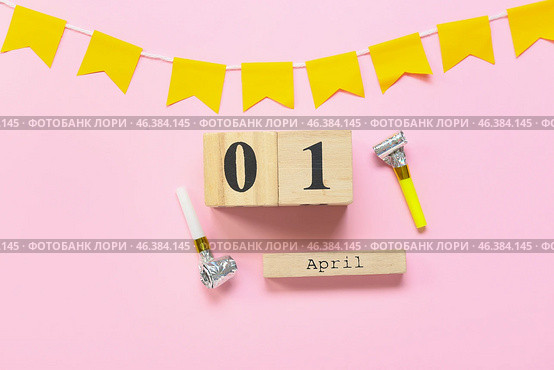 Composition with party whistles and cube calendar with date 1 APRIL on pink background. April Fools Day celebration. Стоковое фото, фотограф Pixel_shot / Фотобанк Лори