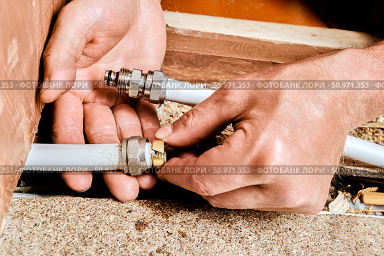 Compression ring is being positioned onto end of multilayer pipe by plumber preparing connection using metal fitting for domestic plumbing line. Стоковое фото, фотограф Владимир Григорьев / Фотобанк Лори