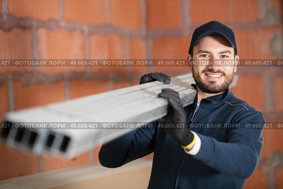 construction worker carrying reinforcement rods at building site. Стоковое фото, агентство Ingram Publishing / Фотобанк Лори