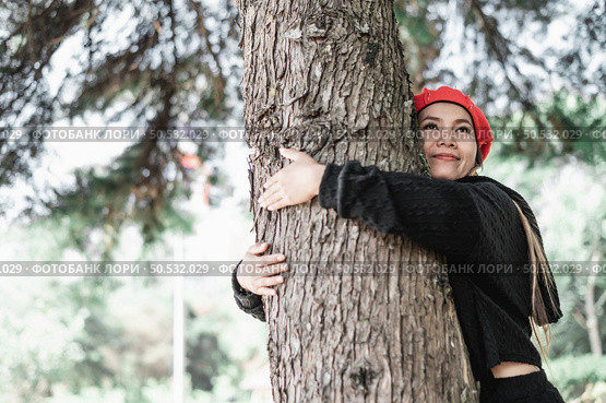 Contented young woman hugging a large tree with a blissful expression with copy space. Concept of care for environment. Стоковое фото, агентство Ingram Publishing / Фотобанк Лори