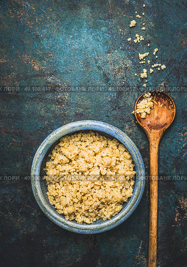 Cooked quinoa in bowl with cooking wooden spoon on dark rustic background, top view, place for text: recipes and menus, vertical. Vegan Superfood, healthy eating and nutrition or diet concept. Стоковое фото, агентство Ingram Publishing / Фотобанк Лори