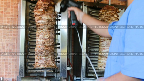 Cooking traditional fast food doner kebab meat on a rotary grill. Стоковое видео, видеограф FotograFF / Фотобанк Лори