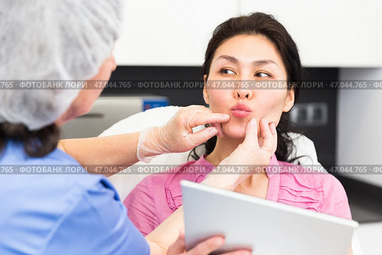 Cosmetologist examining lips of female client before procedure. Стоковое фото, фотограф Яков Филимонов / Фотобанк Лори
