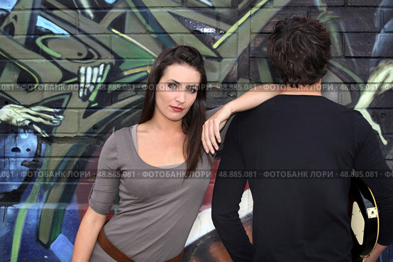 Couple hanging out by a wall painted with graffiti. Стоковое фото, агентство Ingram Publishing / Фотобанк Лори