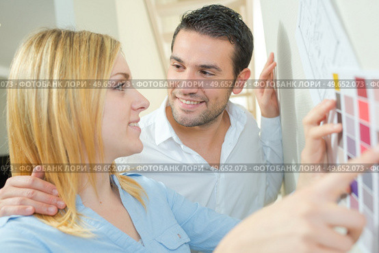 Couple holding color sampler against wall. Стоковое фото, агентство Ingram Publishing / Фотобанк Лори