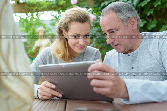 couple looking at photos on tablet. Стоковое фото, агентство Ingram Publishing / Фотобанк Лори