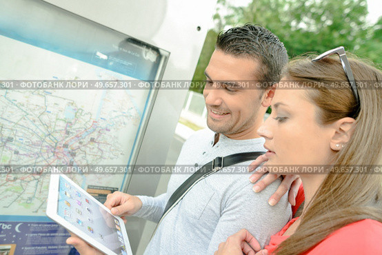 Couple looking at tablet, stood in front of a town map. Стоковое фото, агентство Ingram Publishing / Фотобанк Лори