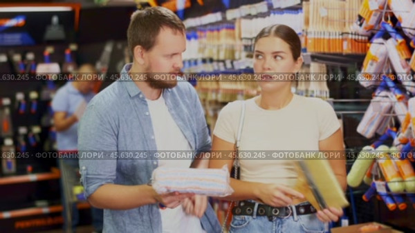 Couple man and woman choosing paint rollers and brushes. Стоковое видео, видеограф Яков Филимонов / Фотобанк Лори