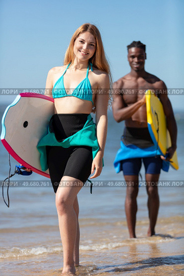 couple of body boarders walking towards sea. Стоковое фото, агентство Ingram Publishing / Фотобанк Лори