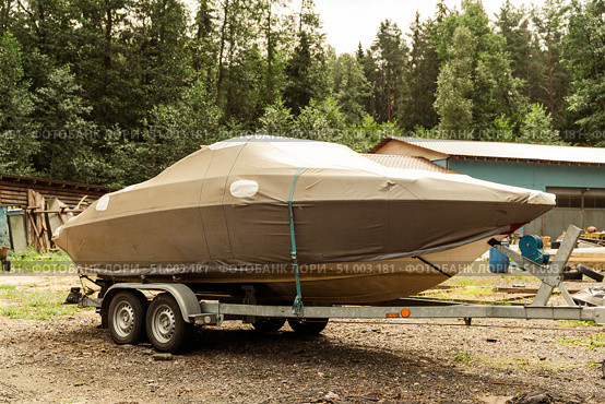 Covered motorboat standing on a trailer in a forest area. Стоковое фото, фотограф Андрей Знаменский / Фотобанк Лори