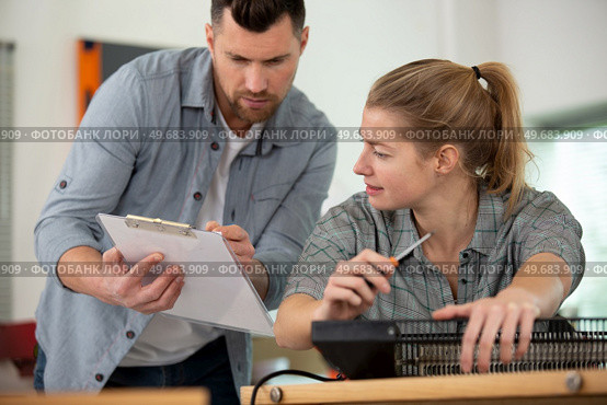 crouching woman with serviceman checking clipboard. Стоковое фото, агентство Ingram Publishing / Фотобанк Лори
