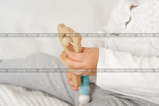 Cute baby girl playing tactile wooden and silicone toys. Young child hand plays sensory massage ball. Enhance the cognitive, physical process. Brain development. Teething toy. Dentition. Baby's teeth. Стоковое фото, фотограф Марина Демидюк / Фотобанк Лори