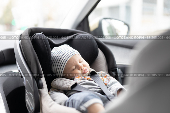 Cute little baby boy sleeping strapped into infant car seat in passenger compartment during car drive. Стоковое фото, фотограф Matej Kastelic / Фотобанк Лори
