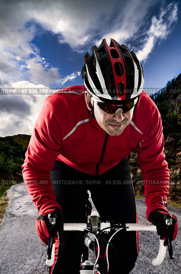 Cyclist on road bike through a asphalt road in the mountains and blue sky with clouds. Стоковое фото, агентство Ingram Publishing / Фотобанк Лори