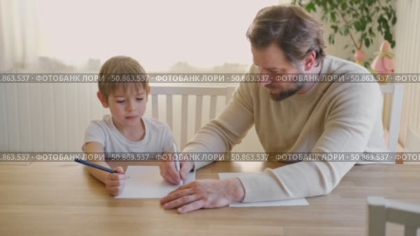 Dad teaches his son writing and counting. Kids primary education. Children learn, study in home school. Daddy male helping teaching little child boy support studying, learning homework. Knowledge day. Стоковое видео, видеограф Марина Демидюк / Фотобанк Лори