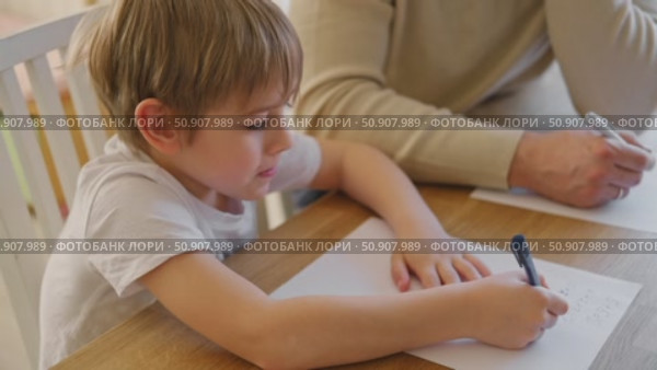 Dad teaches his son writing and counting. Kids primary education. Children learn, study in home school. Daddy male helping teaching little child boy support studying, learning homework. Knowledge day. Стоковое видео, видеограф Марина Демидюк / Фотобанк Лори