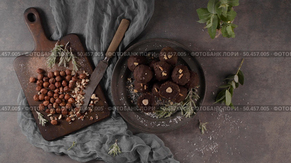 Dark chocolate truffles with hazelnuts and chopped hazelnuts over wooden cutting board. Стоковое фото, агентство Ingram Publishing / Фотобанк Лори