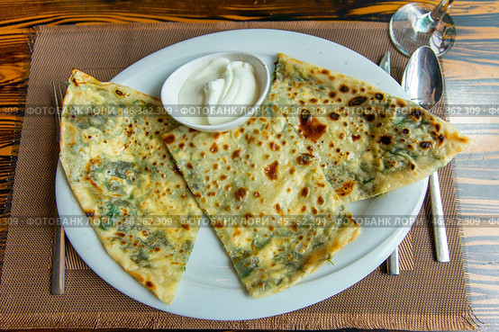 Delicious gourmet flat bread kutabs with herbs and cheese on a plate. Стоковое фото, фотограф Евгений Ткачёв / Фотобанк Лори