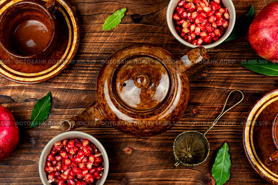 Delicious red tea and pomegranate on table in the teakettle on old wooden rustic background.. Tea With Pomegranate Seeds. Стоковое фото, агентство Ingram Publishing / Фотобанк Лори