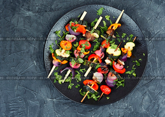 Delicious shashlik of fresh roasted vegetables on wooden skewers on on a concrete kitchen table. Space for text.. Grilled vegetables on skewers, BBQ. Стоковое фото, агентство Ingram Publishing / Фотобанк Лори