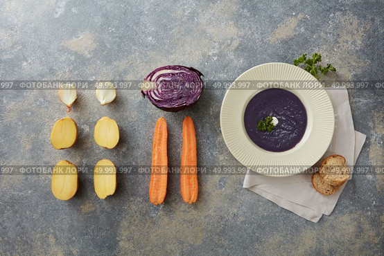 Delicious vegan healthy soup represented near its ingredients: carrot, potato, onion, cabbage. Vegan soup in white plate on table. Some sliced buns near it. Miso soup concept.. Vegan soup over grey. Стоковое фото, агентство Ingram Publishing / Фотобанк Лори