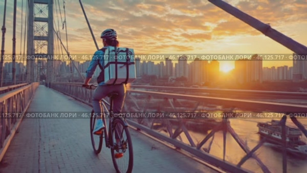 Delivery woman riding bicycle on bridge at sunset. Стоковое AI-видео, аниматор Юрий Поздников / Фотобанк Лори
