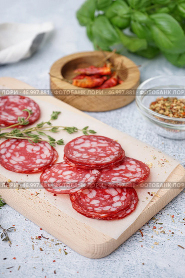 Деревянная доска с ломтями вкусной салями на светлом фоне. Стоковое фото, фотограф Pixel_shot / Фотобанк Лори