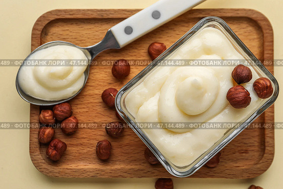Деревянная доска с вкусным ванильным пудингом и фундуком на цветном фоне, крупным планом. Стоковое фото, фотограф Pixel_shot / Фотобанк Лори