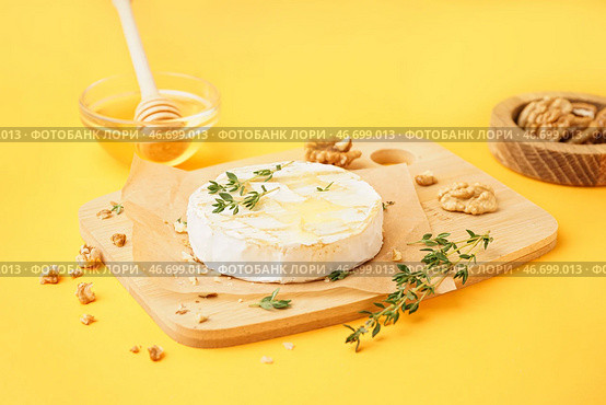 Деревянная доска с вкусным запеченным сыром Камамбер на желтом фоне. Стоковое фото, фотограф Pixel_shot / Фотобанк Лори