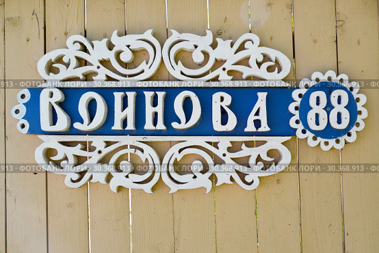 Деревянный резной указатель улицы и дома на дощатом заборе "Воинова 88" (2018 год). Редакционное фото, фотограф Ирина Борсученко / Фотобанк Лори