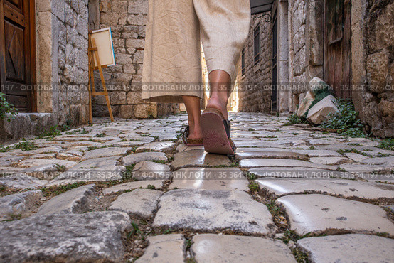 Detail shot of female legs wearing comfortable travel sandals walking on old medieval cobblestones street dring sightseeing city tour. Travel, tourism and adventure concept. Стоковое фото, фотограф Matej Kastelic / Фотобанк Лори