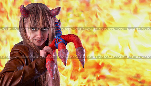 Devil girl with a trident in hands on a background of bright fire. Concept of finding a person in hell. Halloween scene. Стоковое фото, фотограф Дмитрий Кобзев / Фотобанк Лори