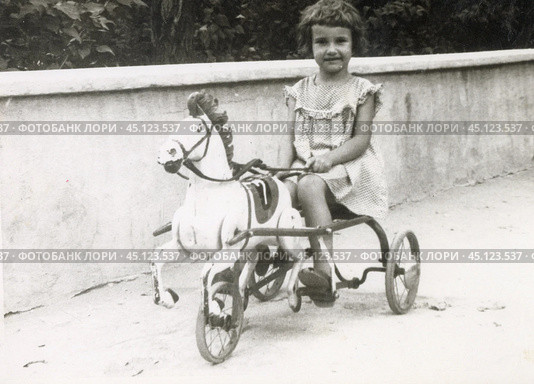 Девочка катается на трёхколёсном велосипеде-лошадке в 1960-х годах. Стоковое фото, фотограф Retro / Фотобанк Лори