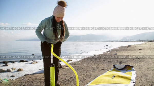 Девушка готовится плавать на sup board по зимнему озеру в Сибири. Озеро Байкал (2016 год). Редакционное видео, видеограф Виталий Зверев / Фотобанк Лори