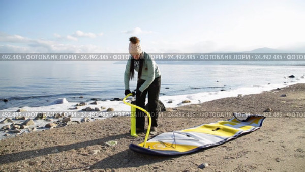 Девушка готовится плавать на sup board по зимнему озеру в Сибири. Озеро Байкал (2016 год). Редакционное видео, видеограф Виталий Зверев / Фотобанк Лори