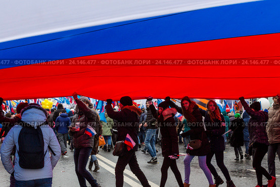 Девушка несет огромное полотнище российского триколора во время шествия и митинга "Мы едины!" в российский праздник День народного единства по Тверской улице в центре города Москвы, Россия 4 ноября 2016. Редакционное фото, фотограф Николай Винокуров / Фотобанк Лори